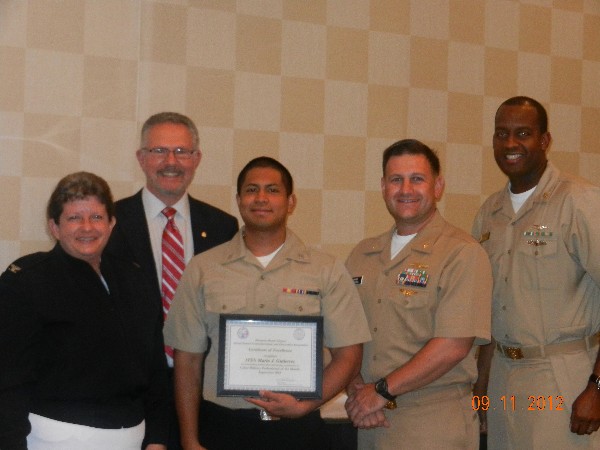 Whit Ludington, chapter president (2nd from l), presents the September Military Cyber Professional Award to Information Systems Technician Seaman Mario Gutierrez, USN (c), as Capt. Barrett (l), Lt. Cmdr. Dave Pereira, USN (2nd from r), chapter vice president for military affairs, and Information Systems Technician Master Chief Jeff Price, USN, stand witness.
